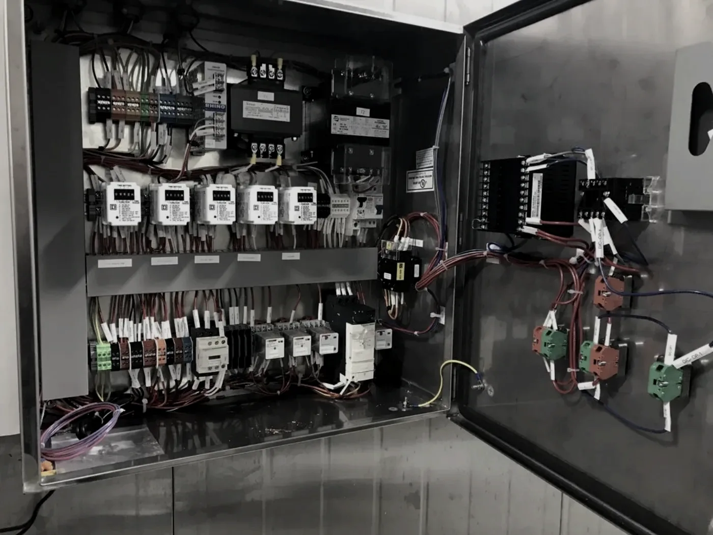 An industrial control panel built by Quantum Power Quality: a stainless enclosure open to show timers, contactors, terminal blocks and labelled wiring